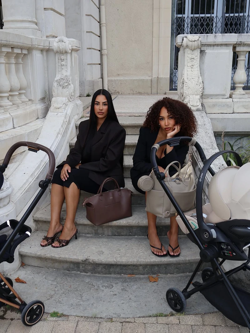 Deux mamans assises sur des marches avec leurs poussettes et leurs sacs ALBA