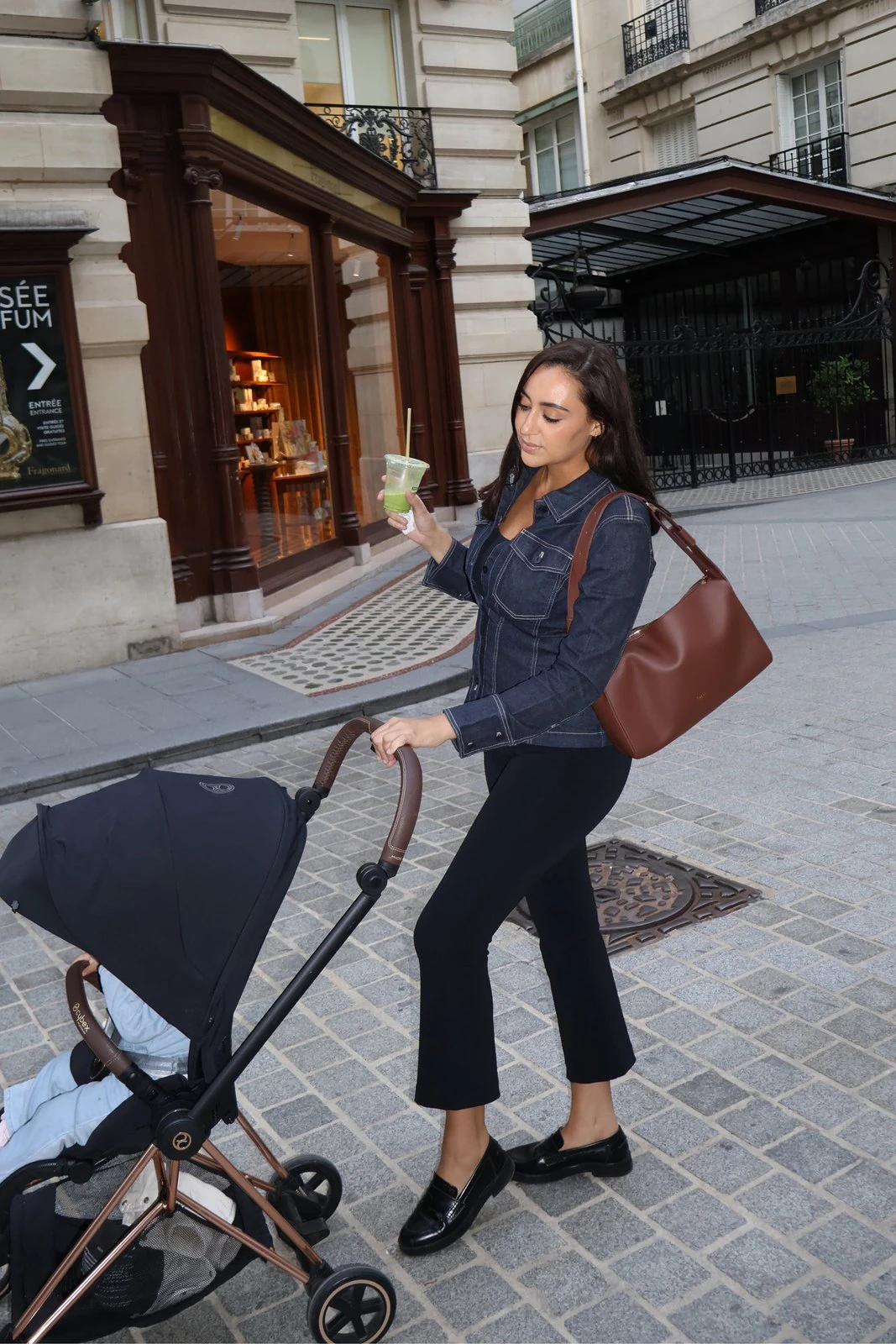 Une maman pousse la poussette dans une rue de Paris, son sac MILA à l’épaule
