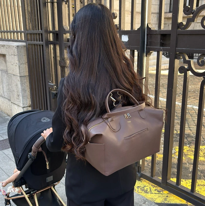 Une maman rentre avec la poussette, le sac ALBA porté en sac à dos